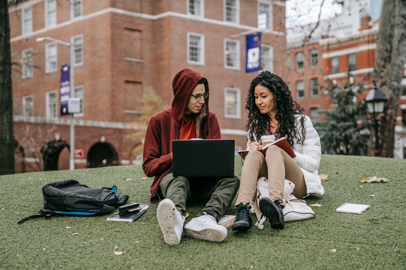 Two students studying together on a campus lawn